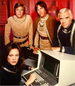 Promotional shot for the 1978 series Battlestar Galactica. Form left to right: Lieutenant Athena (played by Maren Jensen), Lieutenant Starbuck (Dirk Benedict), Captain Apollo (Richard Hatch), and Commander Adama (Lorne Greene).