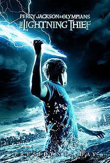 A youth, standing in a large body of water in the dark, holds a bolt of lightning in his raised right arm and faces away, towards a city skyline, The Lightning Thief