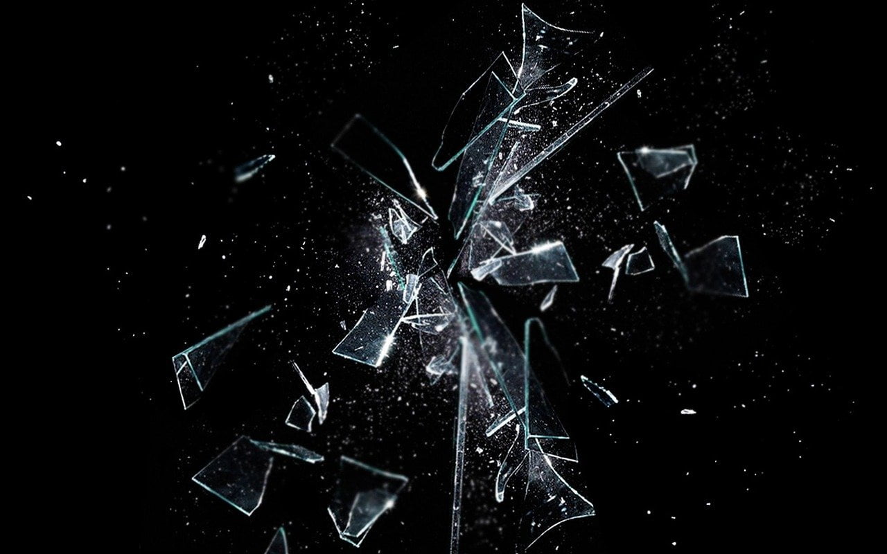 Glass bursts into scattered fragments against a black background.
