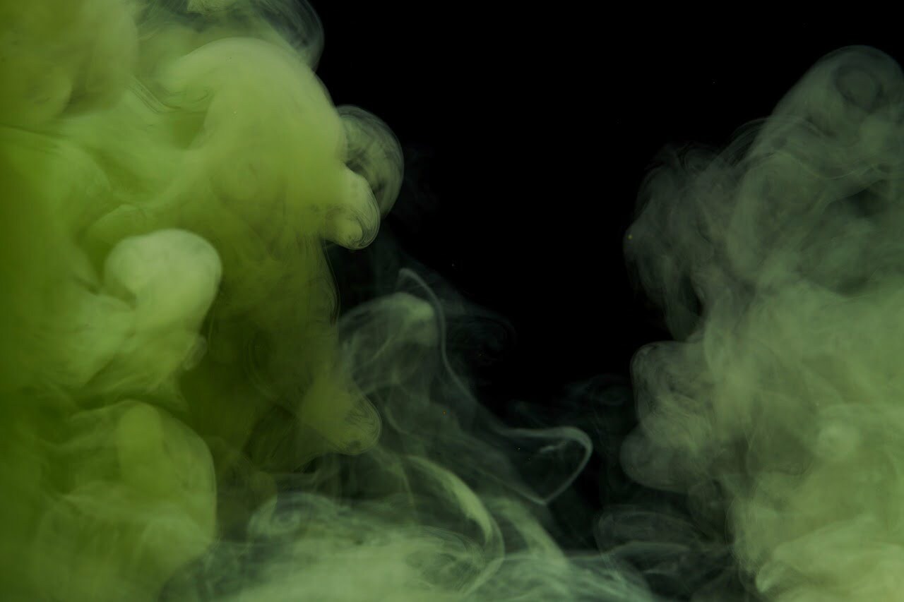 Green clouds of ink curl across a black background.